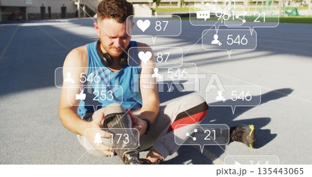 Adjusting prosthetic leg, man sitting on blue track wearing sportswear, floating social media icons Adjusting prosthetic leg, man sitting on blue track wearing sportswear, floating social media icons 135443065