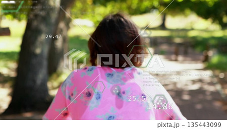 Walking teenage female wearing bright pink floral top following paved park path, with HUD graphics 135443099