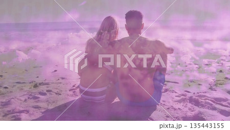 Sitting couple wearing blue trunks and striped bikini on sandy beach, with ocean waves and horizon Sitting couple wearing blue trunks and striped bikini on sandy beach, with ocean waves and horizon 135443155