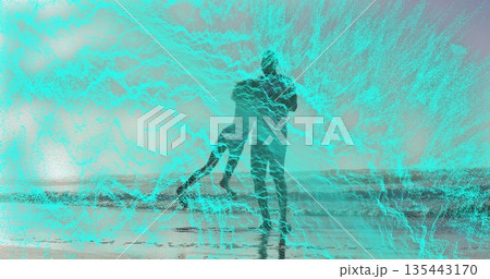 Swinging man and child playing at ocean shoreline, with wet sand and gentle waves 135443170