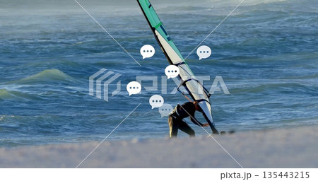 Adjusting windsurf sail to board, male in wetsuit on sandy shoreline with rigging lines, copy space Adjusting windsurf sail to board, male in wetsuit on sandy shoreline with rigging lines, copy space 135443215