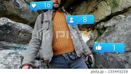 Standing hiker wearing wide-brimmed hat at cave entrance, with camera, backpack, social media icons Standing hiker wearing wide-brimmed hat at cave entrance, with camera, backpack, social media icons 135443259