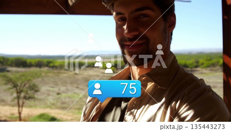 Shirt-wearing man taking selfie on veranda over plain, with blue 75-notification bubble, copy space 135443273