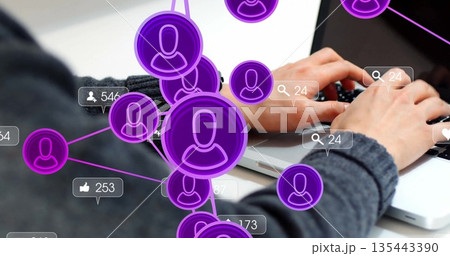 Typing analyst wearing sweater analyzing purple nodes with metric bubbles on laptop at office desk 135443390