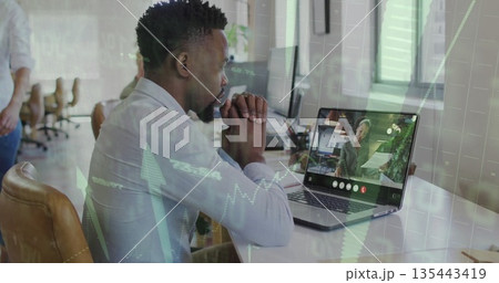 Leaning man wearing button-up shirt and dark pants focusing on laptop at open office, with plant Leaning man wearing button-up shirt and dark pants focusing on laptop at open office, with plant 135443419