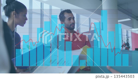 Two colleagues wearing business attire analyzing graph overlay in office, with laptop and folders Two colleagues wearing business attire analyzing graph overlay in office, with laptop and folders 135443503