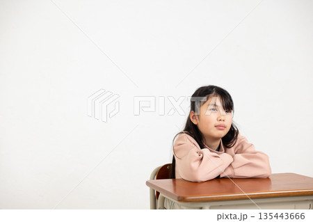 学習机で腕を組む小学生の女の子 135443666