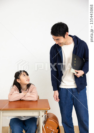 教室で会話する男性教諭と小学生の女の子 教室で会話する男性教諭と小学生の女の子 135443868