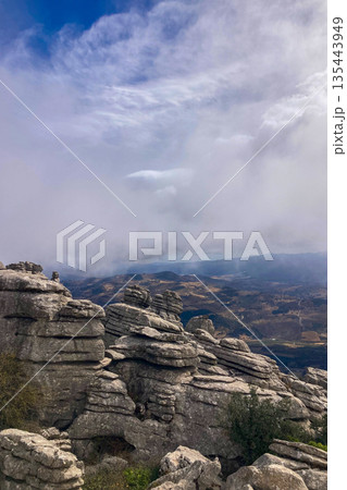 A mystical morning walk through the rocky landscapes of Torcal de Antequera in Andalusia, Spain, as soft mist drifts under the gentle rays of the sun. 135443949