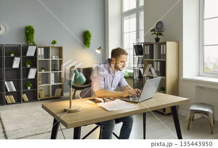 Workaholic man working late with laptop on online project at office desk in night 135443950