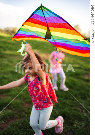 Children joyfully flying a colorful kite on a sunny afternoon 135444064