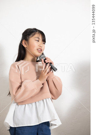 マイクを持って歌を歌う小学生の女の子 マイクを持って歌を歌う小学生の女の子 135444099