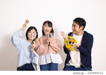 カラオケを楽しむ小学生の女の子と盛り上げる両親 135444111
