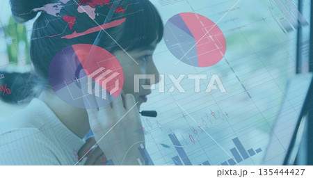 Monitoring call center agent analyzing financial charts on monitor in office, with headset mic Monitoring call center agent analyzing financial charts on monitor in office, with headset mic 135444427