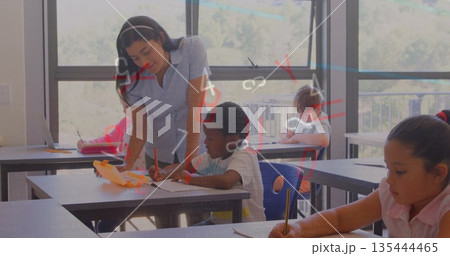 Leaning female teacher offering one-on-one assistance in classroom, with headphones and notebooks 135444465