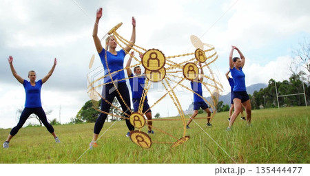 Six adults wearing blue tops black pants stretching on grassy field, with golden orb and goalposts 135444477