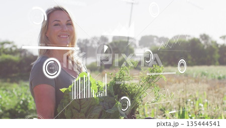 Holding leafy greens, female farmer viewing farming data overlays in vegetable field, copy space 135444541