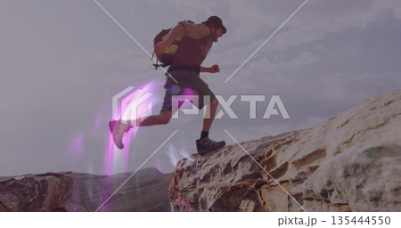 Leaping adult male hiker navigating desert canyon ridge, with daypack backpack and hiking boots 135444550