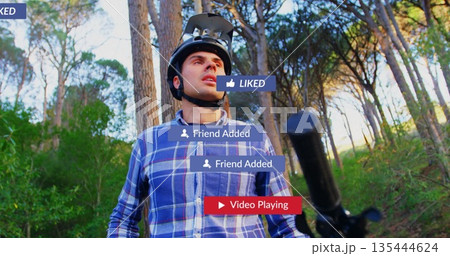Standing man wearing bicycle helmet and blue plaid shirt on wooded trail, with social media icons 135444624