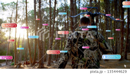 Walking hunter in camouflage with crossbow at dusk pine forest, with data tags and numeric overlays 135444629