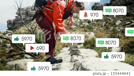 Hiker in red coat placing stone on rocky hill, with backpack rope alerts, copy space 135444641