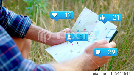 Man in checkered shirt and shorts examining clipboard map in grassy field with social media icons 135444646
