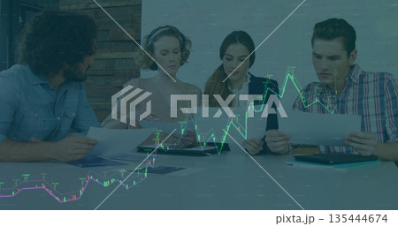Colleagues analyzing stock market data on charts in office, with tablet and folder 135444674