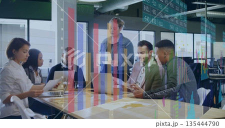 Six professionals collaborating around conference table in office, with laptops, reports and charts Six professionals collaborating around conference table in office, with laptops, reports and charts 135444790