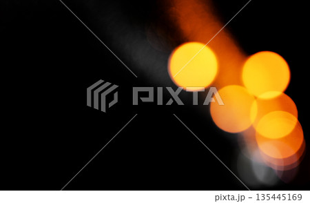 Bokeh lights in night. Large golden orange circles glow with brilliance on dark background leaving 135445169