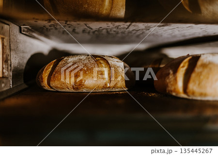Fresh buns from the oven. Conveyor with bread. Baking bread. Workshop for production of bread. White bread in the oven. Hot buns. Confectionery. 135445267