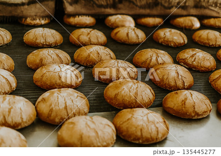 Fresh buns from the oven. Conveyor with bread. Baking bread. Workshop for production of bread. White bread in the oven. Hot buns. Confectionery Fresh buns from the oven. Conveyor with bread. Baking bread. Workshop for production of bread. White bread in the oven. Hot buns. Confectionery 135445277