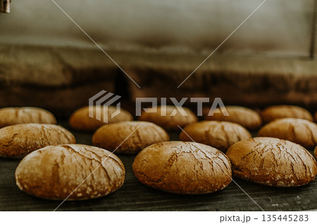 Fresh buns from the oven. Conveyor with bread. Baking bread. Workshop for production of bread. White bread in the oven. Hot buns. Confectionery Fresh buns from the oven. Conveyor with bread. Baking bread. Workshop for production of bread. White bread in the oven. Hot buns. Confectionery 135445283