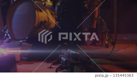 Pressing musician's leather boot activating guitar pedals on stage, with bass drum and audio cables Pressing musician's leather boot activating guitar pedals on stage, with bass drum and audio cables 135445363