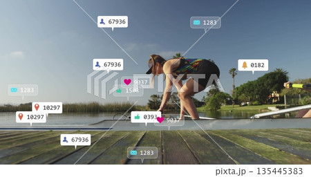 Crouching woman athlete wearing visor holding rowing shell steady on dock, with social media icons Crouching woman athlete wearing visor holding rowing shell steady on dock, with social media icons 135445383