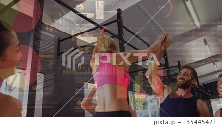 Performing pull-up on metal bar woman wearing pink top training in gym, with analytics overlays 135445421