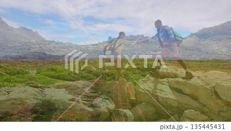 Reaching female hiker grabbing partner's hand while climbing on rocky slope, with backpacks, boots 135445431