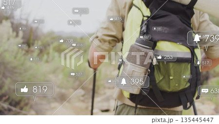 Hiking man wearing tan outfit on dusty trail with backpack, poles and floating icons, copy space 135445447