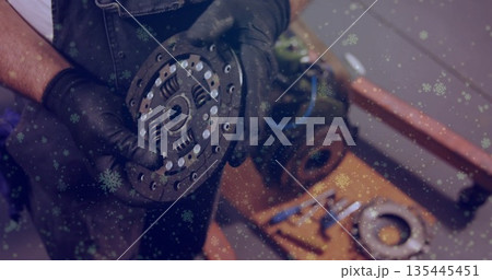 Inspecting gloved mechanic examining clutch plate on workbench in garage, with gearbox and wrenches Inspecting gloved mechanic examining clutch plate on workbench in garage, with gearbox and wrenches 135445451