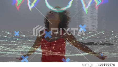 Standing woman in red sleeveless dress stretching arms on beach, with digital mesh glitch overlay 135445470