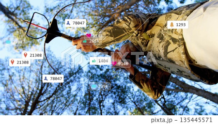 Scanning outdoorsman holding metal detector in pine forest, floating social media icons, copy space 135445571