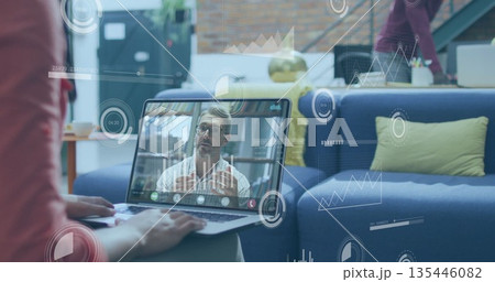 Typing woman connecting with mature man on laptop screen in living room, with infographic overlays 135446082