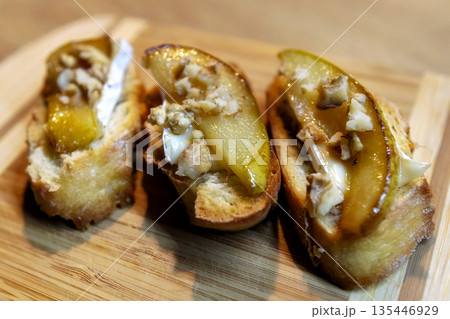 Pear bruschetta with white cheese and walnuts 135446929