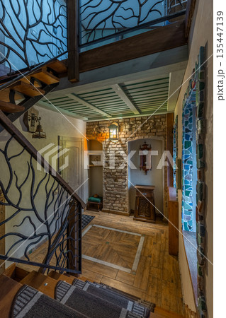 Rustic hallway interior with tree branch wrought iron stairs and brick wall Rustic hallway interior with tree branch wrought iron stairs and brick wall 135447139