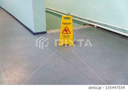 Caution sign placed on floor near stairs in a building hallway area Caution sign placed on floor near stairs in a building hallway area 135447534
