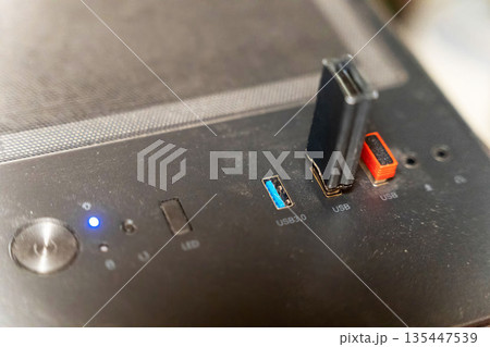 USB ports on a computer case with lights and connectors visible while in use 135447539