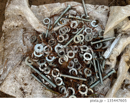 Scattered metal fasteners and hardware on a white tarp outdoors in autumn Scattered metal fasteners and hardware on a white tarp outdoors in autumn 135447605