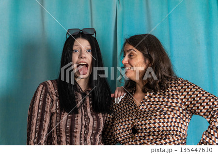 Women share a fun moment with playful expressions in a photo booth setting Women share a fun moment with playful expressions in a photo booth setting 135447610