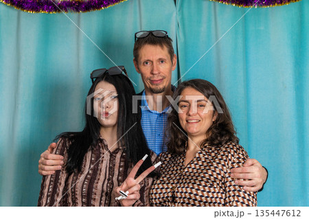 Group poses together in front of a blue backdrop with party decorations Group poses together in front of a blue backdrop with party decorations 135447612