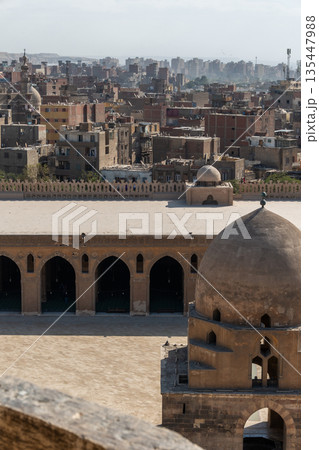 Ibn Tulun Mosque in Cairo features a large dome and intricate architectural details. The structure showcases Islamic design elements and historical significance. Ibn Tulun Mosque in Cairo features a large dome and intricate architectural details. The structure showcases Islamic design elements and historical significance. 135447988