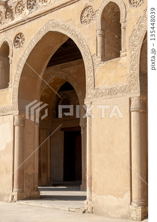 A corridor in the Ibn Tulun mosque with tall columns and intricate patterns. Soft light filters through, creating shadows. A corridor in the Ibn Tulun mosque with tall columns and intricate patterns. Soft light filters through, creating shadows. 135448039